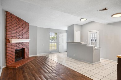 Kitchen featuring a textured ceiling, light tile patterned flooring, and a brick fireplace