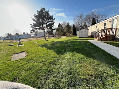 View of grassy yard with a playground and a storage shed