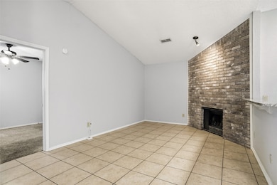 Unfurnished living room featuring lofted ceiling, light tile patterned flooring, a brick fireplace, and ceiling fan
