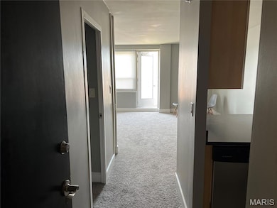 Hallway featuring light colored carpet and baseboards