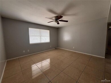Tiled spare room featuring baseboards and ceiling fan