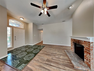 Entryway with wood finished floors, ceiling fan, and a brick fireplace