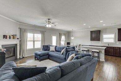 Living room featuring plenty of natural light, a ceiling fan, recessed lighting, crown molding, and a glass covered fireplace