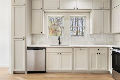 Kitchen with appliances with stainless steel finishes, tasteful backsplash, light hardwood / wood-style floors, and sink