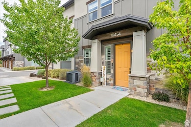 View of exterior entry featuring stone siding, board and batten siding, and a yard