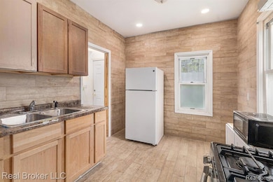 Kitchen with black appliances, tile walls, light wood finished floors, recessed lighting, and light brown cabinets