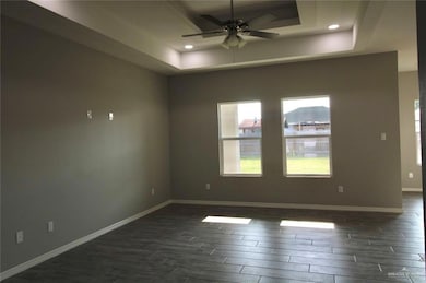 Unfurnished room featuring a raised ceiling, wood tiled floors, a ceiling fan, baseboards, and recessed lighting