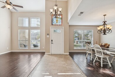 Entrance foyer with a chandelier, dark wood-type flooring, a high ceiling, and inlaid floor details