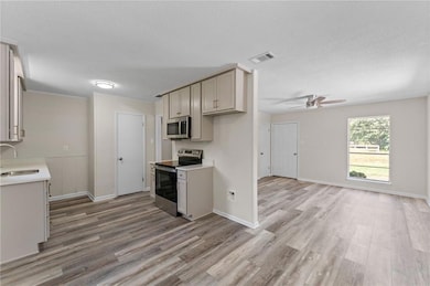Kitchen with appliances with stainless steel finishes, light wood-style flooring, a ceiling fan, a textured ceiling, and open floor plan
