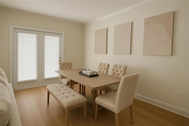 Dining area with wood finished floors, ornamental molding, and baseboards