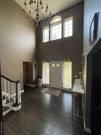 Entryway with stairway, wood finished floors, a chandelier, and a towering ceiling