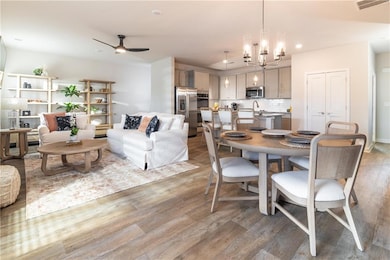 Dining room with ceiling fan with notable chandeli