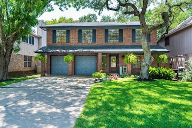 Traditional home with brick siding, a front yard, concrete driveway, covered porch, and a garage