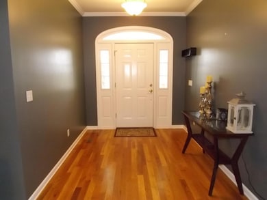 Entry foyer with hardwood flooring and beautiful front door.