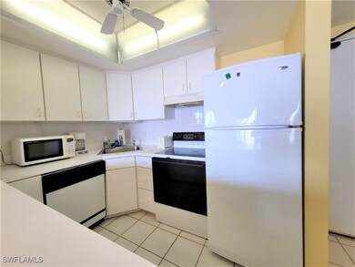 Kitchen featuring white appliances, light countertops, light tile patterned floors, and white cabinetry