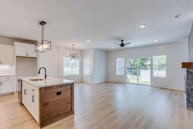 Kitchen with sink, light hardwood / wood-style flooring, white cabinetry, and an island with sink