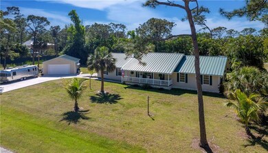 View of front of property with driveway, a standing seam roof, an outbuilding, metal roof, and a porch