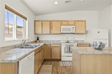 Kitchen with white appliances, light countertops, light brown cabinetry, light wood finished floors, and recessed lighting