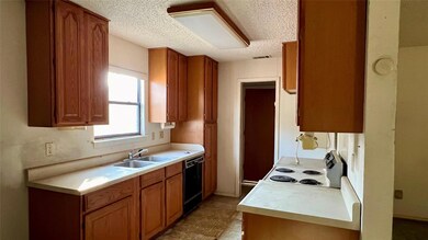 Kitchen featuring stove, black dishwasher, sink, l