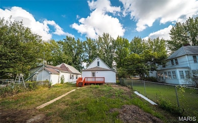 Fenced backyard featuring a wooden deck and view of scattered trees