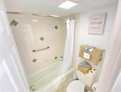 Full bathroom with shower / tub combo, toilet, and tile patterned floors