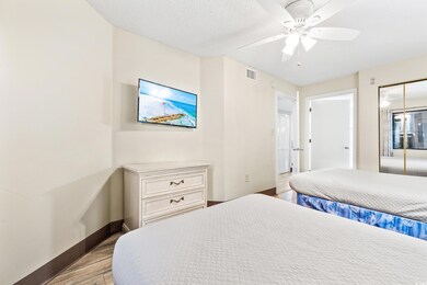 Bedroom with a textured ceiling, light hardwood / 