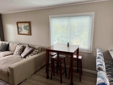 Living room featuring crown molding, baseboards, wood finished floors, and a healthy amount of sunlight