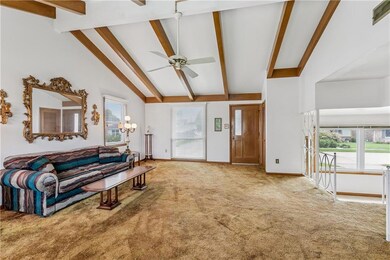 Living room view looking towards the front of the house & overlooking the dining room & art deco iron railing. Includes a closet next to the front door. Seller believes their are wood floors under the carpet.