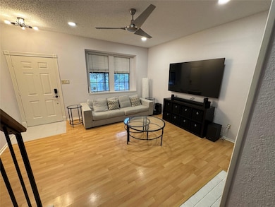 Living room featuring ceiling fan, light wood-sty