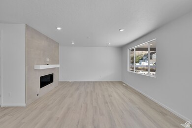 Unfurnished living room featuring a fireplace, light wood-style floors, recessed lighting, and a textured ceiling