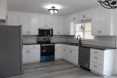 Kitchen featuring dark countertops, white cabinets