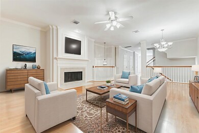 Expansive and light-filled, the second-floor living area features gleaming hardwood floors, elegant crown molding, and a gaslog fireplace framed by custom millwork and decorative wall paneling. Multiple windows with plantation shutters invite natural light while maintaining privacy. This open-concept space seamlessly blends style and comfort.