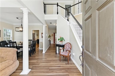 Foyer entrance featuring light wood finished floors, stairway, crown molding, and a towering ceiling