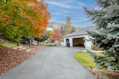 View of side of home with a mountain view, a garage, driveway, and stucco siding