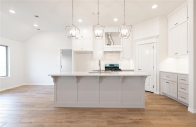 Kitchen featuring decorative backsplash, white cabinets, light wood finished floors, a breakfast bar, and recessed lighting