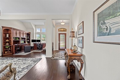 This is an elegant, well-lit open home office with hardwood floors is enhanced by tall windows allowing for natural light.