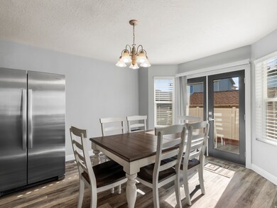 Dining area featuring a textured ceiling, healthy amount of natural light, wood finished floors, and a chandelier