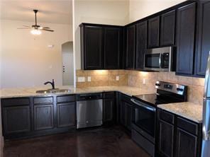 Kitchen with stainless steel appliances, tasteful backsplash, dark cabinets, arched walkways, and a peninsula