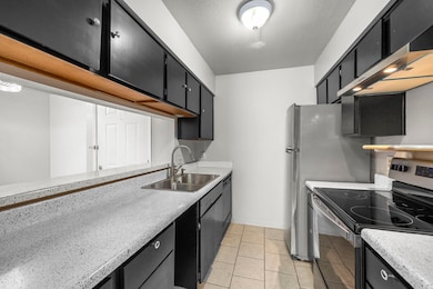 The Galley kitchen features freshly painted cabinets, recent Whirlpool electric stove with range hood + double basin sink (2023), and a newer stainless steel refrigerator.