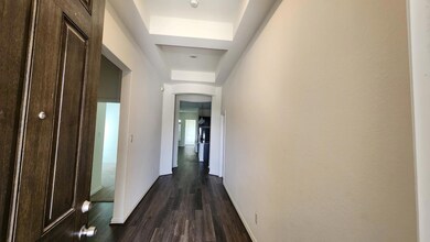 Hall featuring a tray ceiling, dark wood-style fl