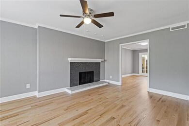 Unfurnished living room featuring crown molding, wood finished floors, a ceiling fan, and a tile fireplace