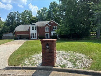 View of front of home featuring driveway, an attached garage, and view of wooded area
