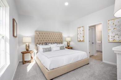 Bedroom with light colored carpet, connected bathr