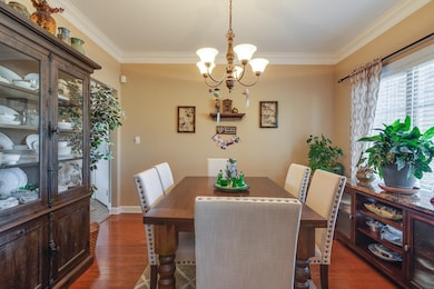 Dining room with wood finished floors, crown molding, and a chandelier