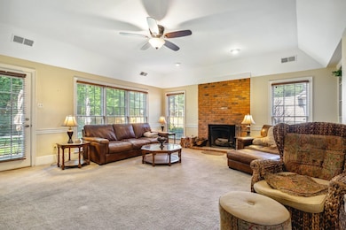 Carpeted living room with brick wall, a fireplace,