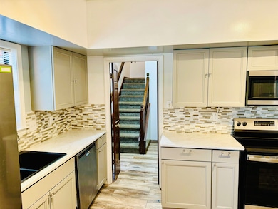 Kitchen featuring stainless steel appliances, light wood finished floors, light stone counters, and decorative backsplash