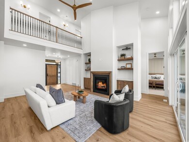 Living room with a ceiling fan, a high ceiling, built in features, recessed lighting, and a glass covered fireplace