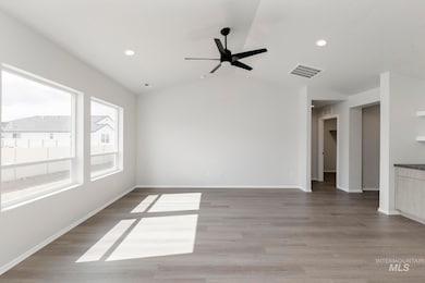 Unfurnished room featuring light wood finished floors, vaulted ceiling, ceiling fan, and recessed lighting