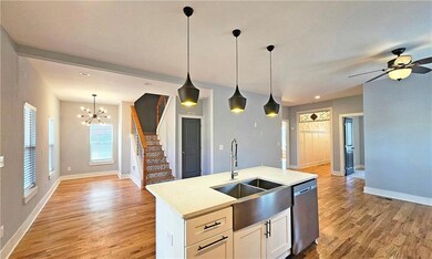 Kitchen with pendant lighting, sink, white cabinetry, a center island with sink, and stainless steel dishwasher