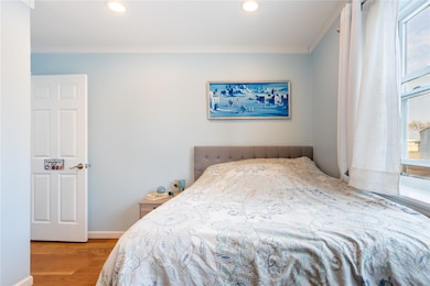 Bedroom with recessed lighting, wood finished floors, baseboards, and ornamental molding
